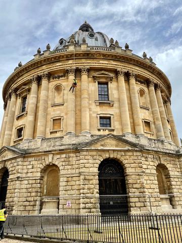 A man abseiling over the edge of the Radcliffe Camera