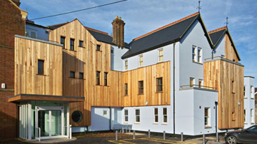 Photo of the exterior of Boundary Brook House, painted light blue and featuring wooden cladding